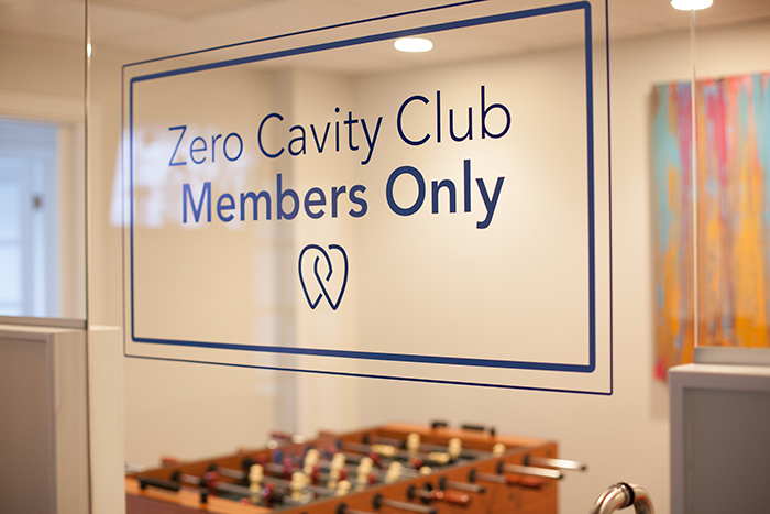 The image shows a sign on a glass door indicating that the establishment is a zero cavity club, welcoming members only.