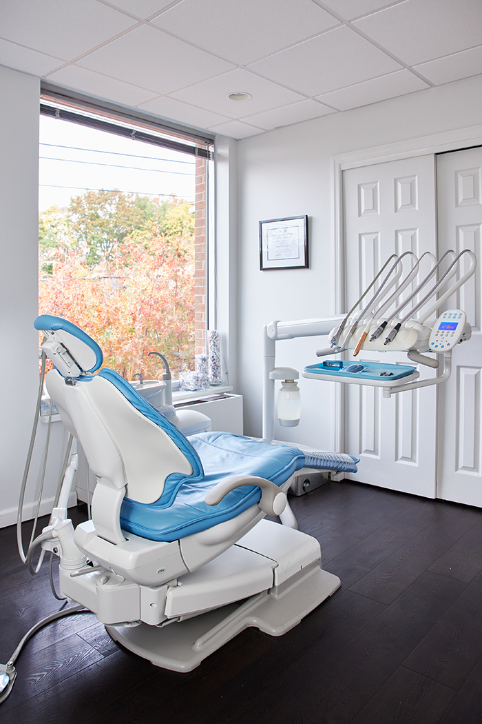 The image shows a dental office with modern equipment, including a dentist s chair and a treatment table.