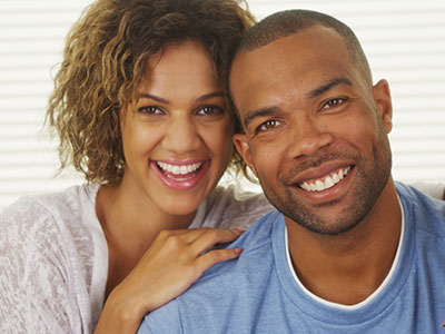 A man and woman posing closely together with smiles on their faces.