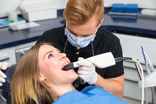 Woman receiving dental treatment from dentist with drill in her mouth.