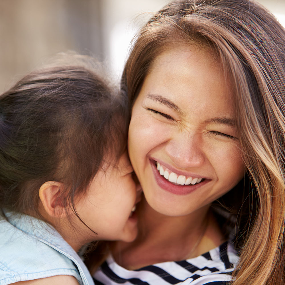 A woman embracing a child with a smile on her face.